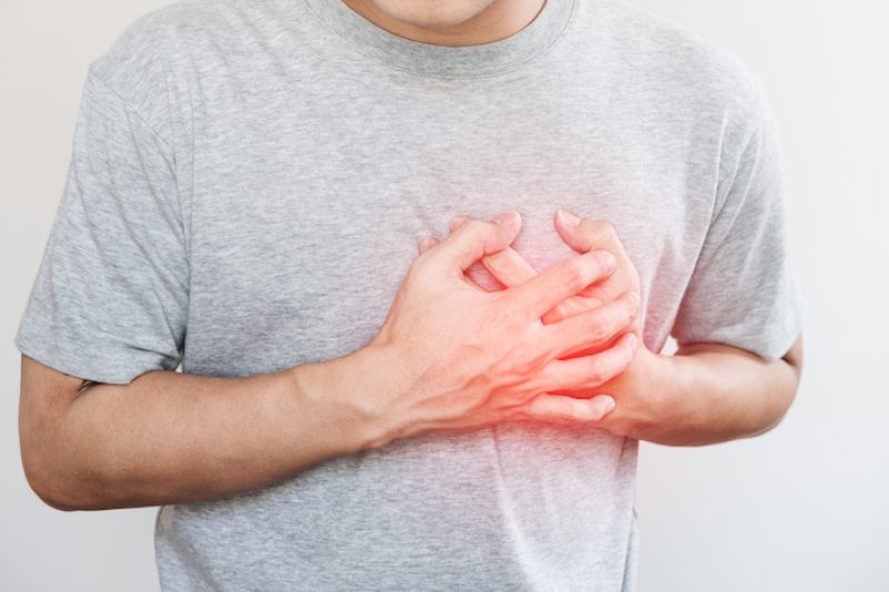 a man touching his heart, with red highlight of heart attack, and others heart disease concept, on white background